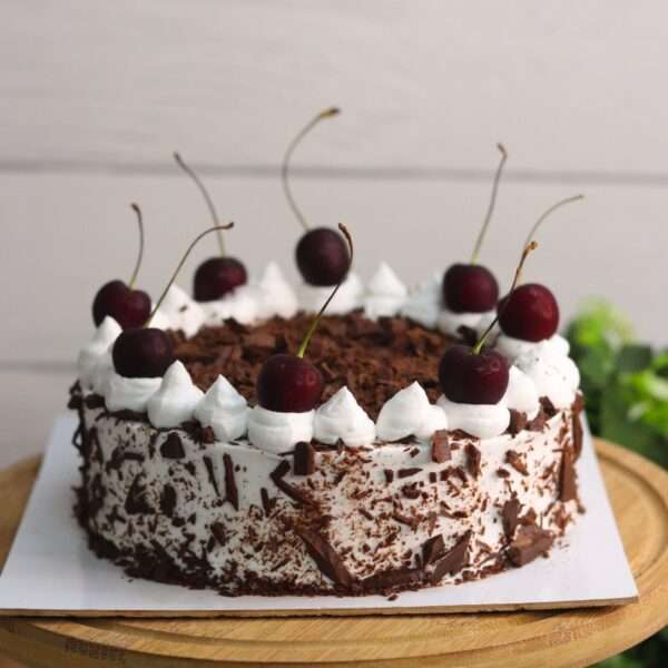 A rich chocolate cake known as 'Black Forest Cake,' featuring whipped cream and cherries, topped with chocolate shavings and whole cherries.