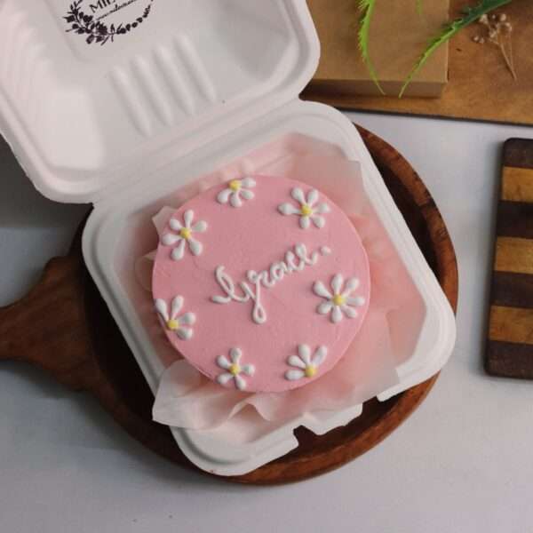A pink bento cake with white and yellow flower design