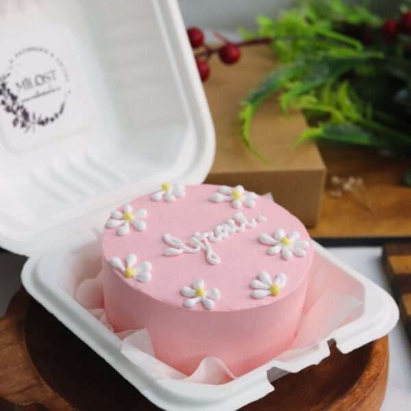 A pink bento cake with white and yellow flower design